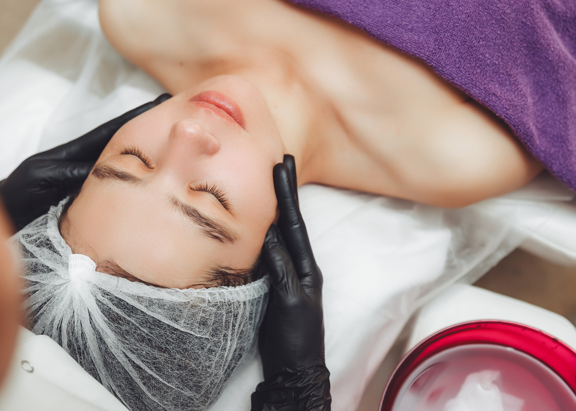 The cosmetologist's hands do a manual relaxing rejuvenating facial massage for a young woman in a beauty salon. Rejuvenating facial massage